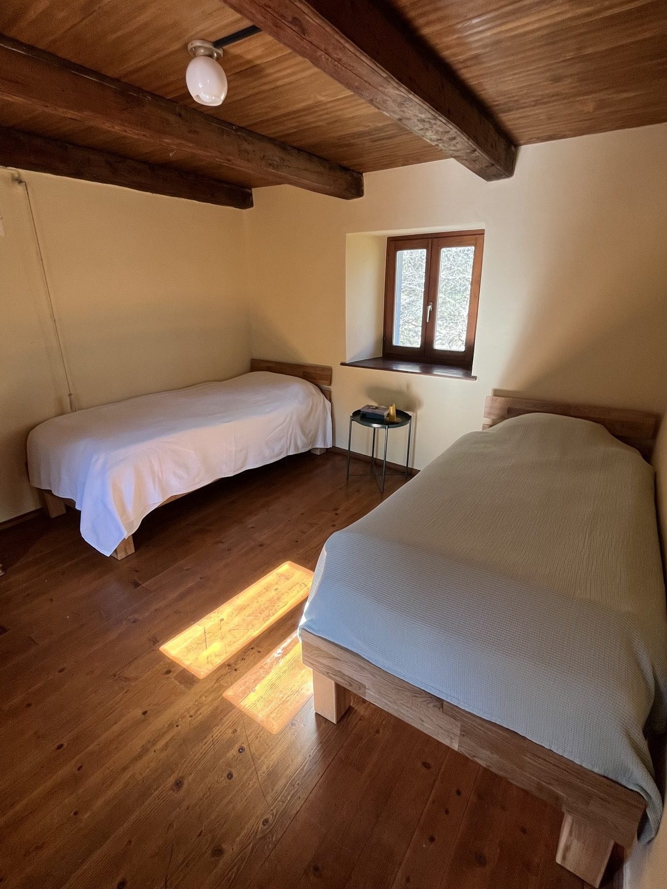 Zweibettzimmer mit Holzboden und Sonnenlicht