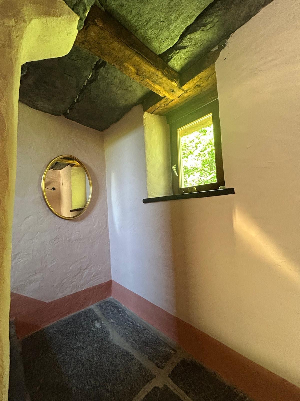 Treppenhaus mit rundem Spiegel und Natursteinboden
