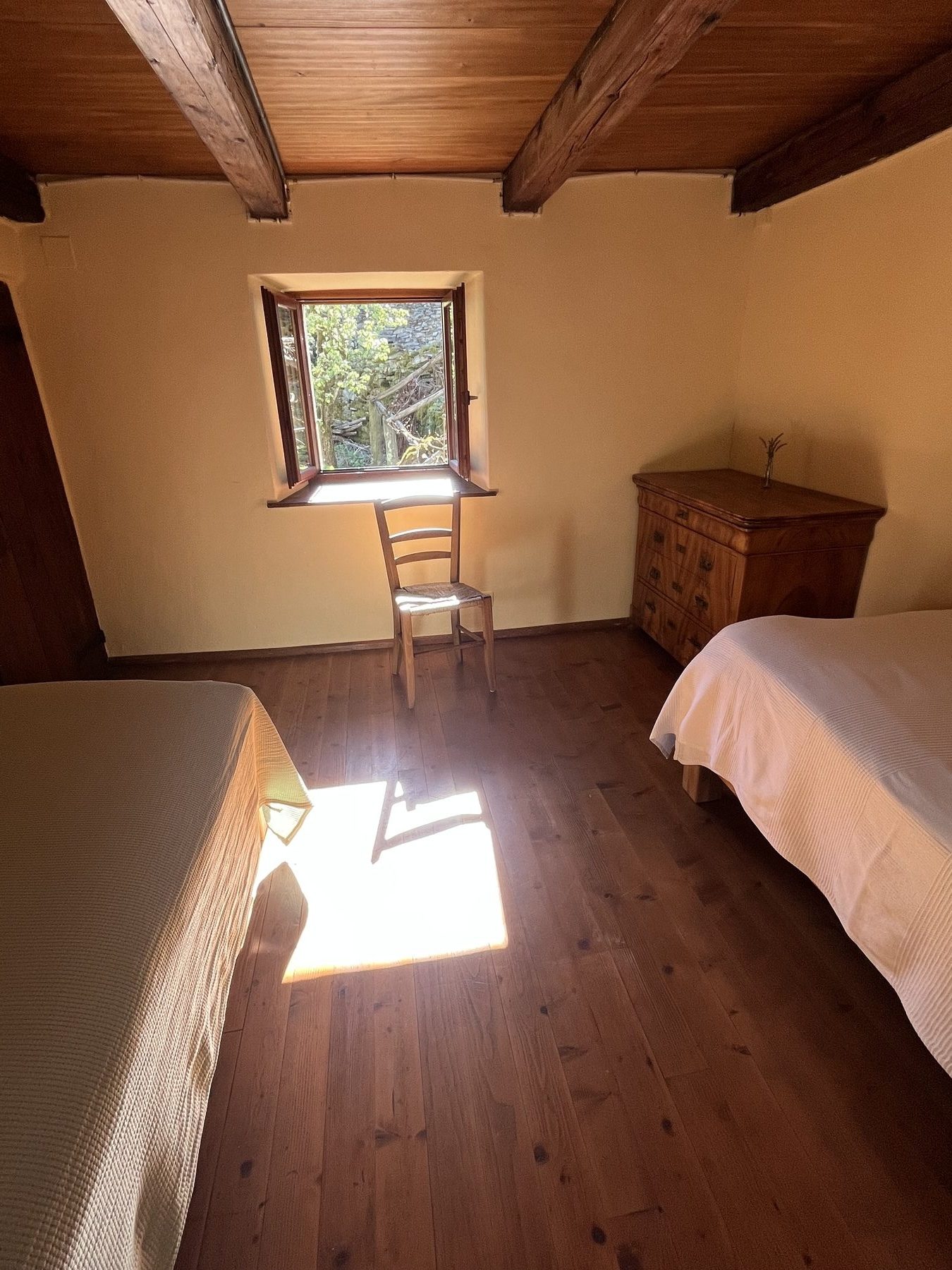 Zweibettzimmer mit Holzbalken und Sonnenlicht